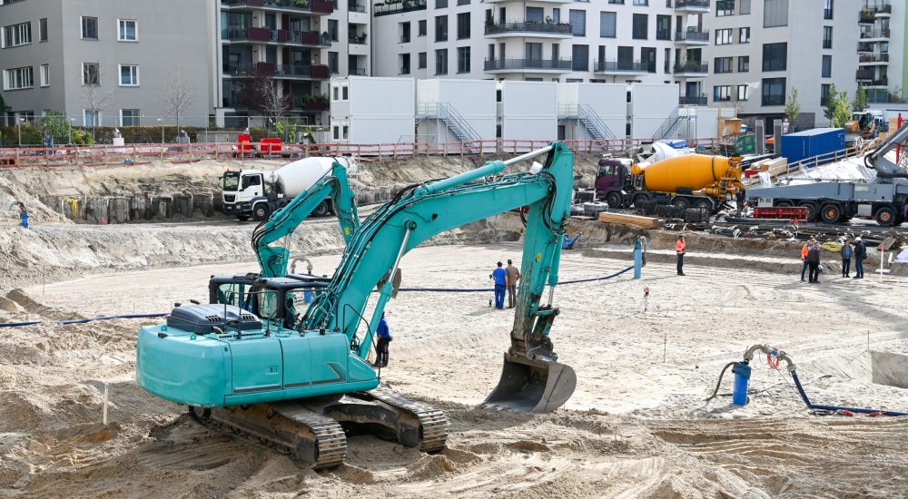 A large aquamarine excavator being used for site preparation in Iowa.